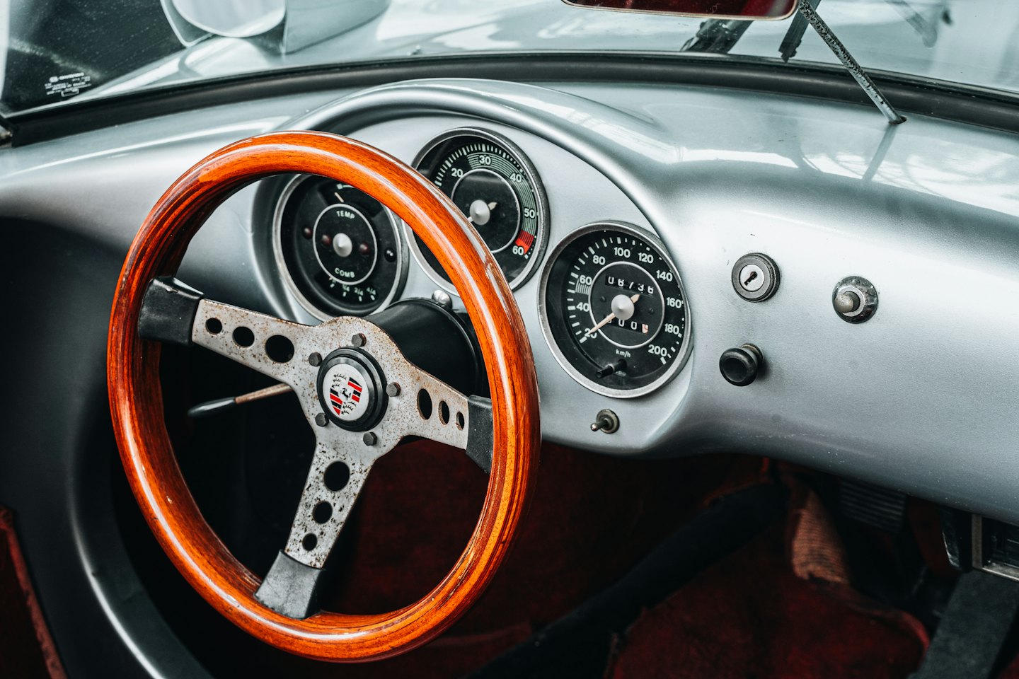 Armaturenbrett eines Oldtimers mit hölzernem Lenkrad und Anzeigen.